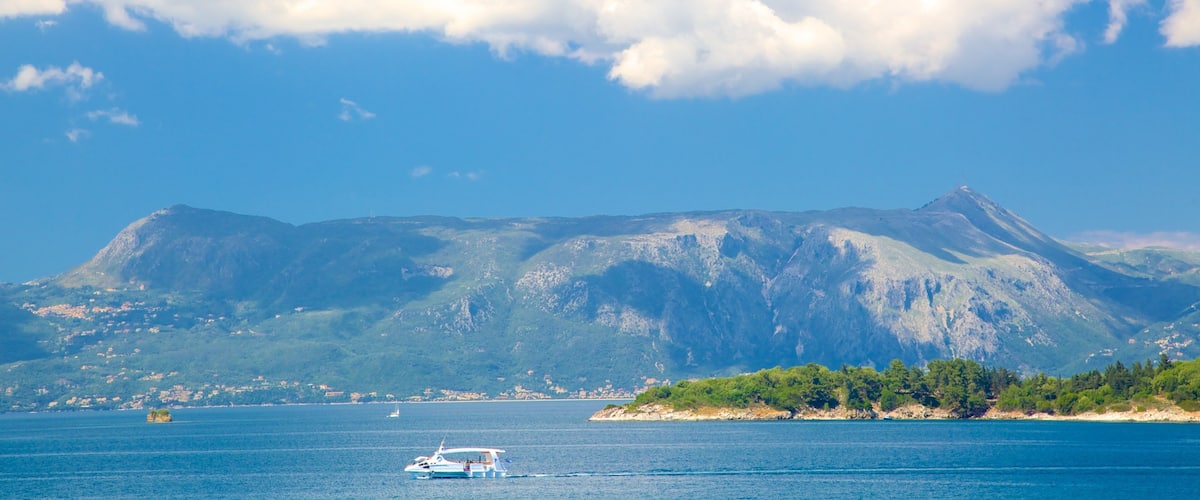 A boat on a calm sea with a mountain range in the background.