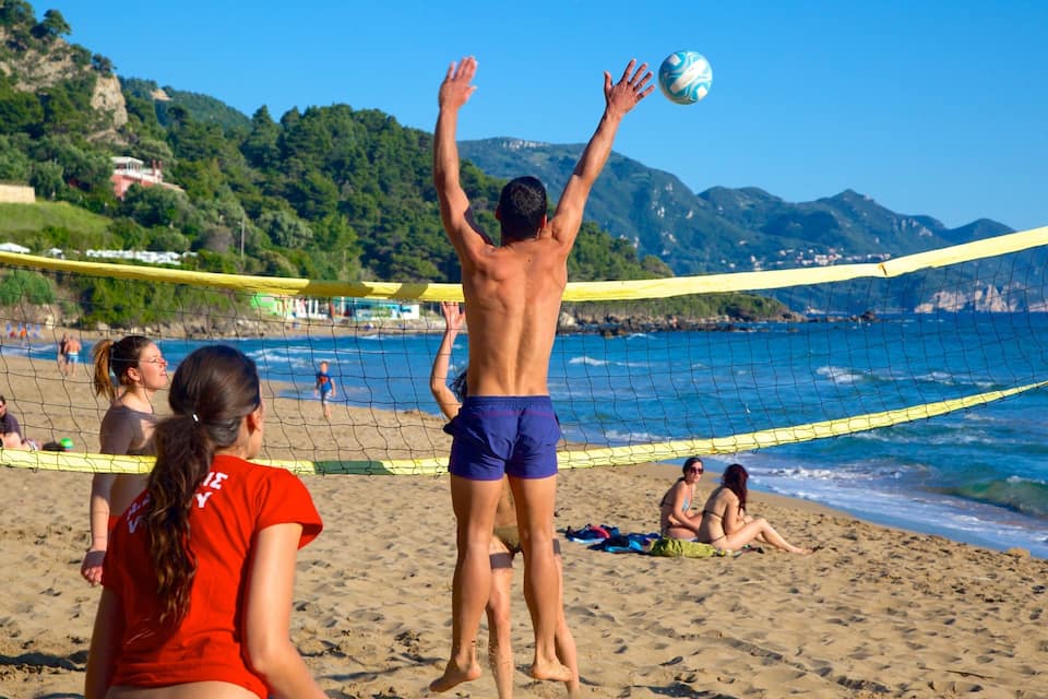 A beach volleyball game with players and spectators.