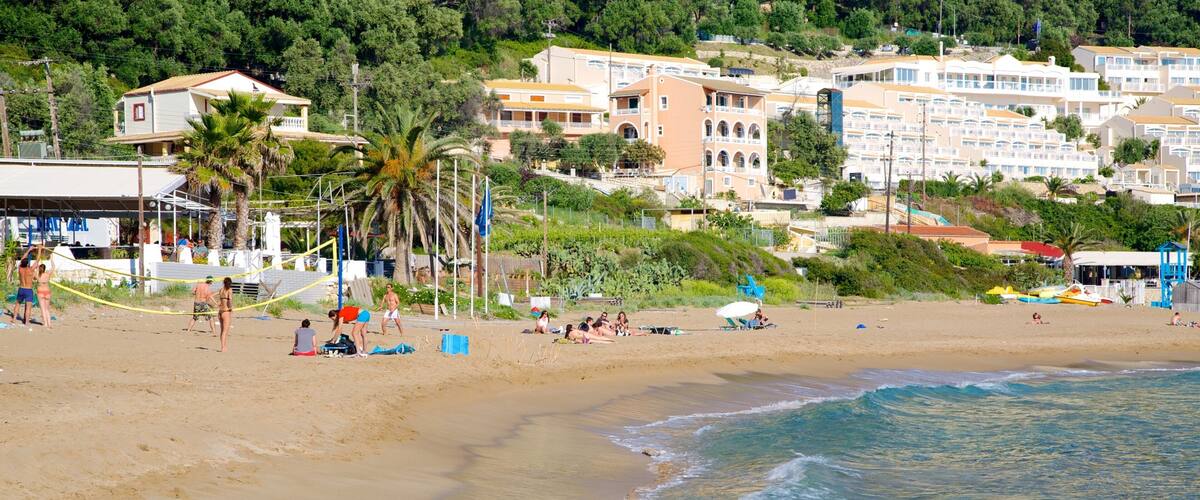 A beach with people sunbathing and playing volleyball, palm trees, and buildings in the background.