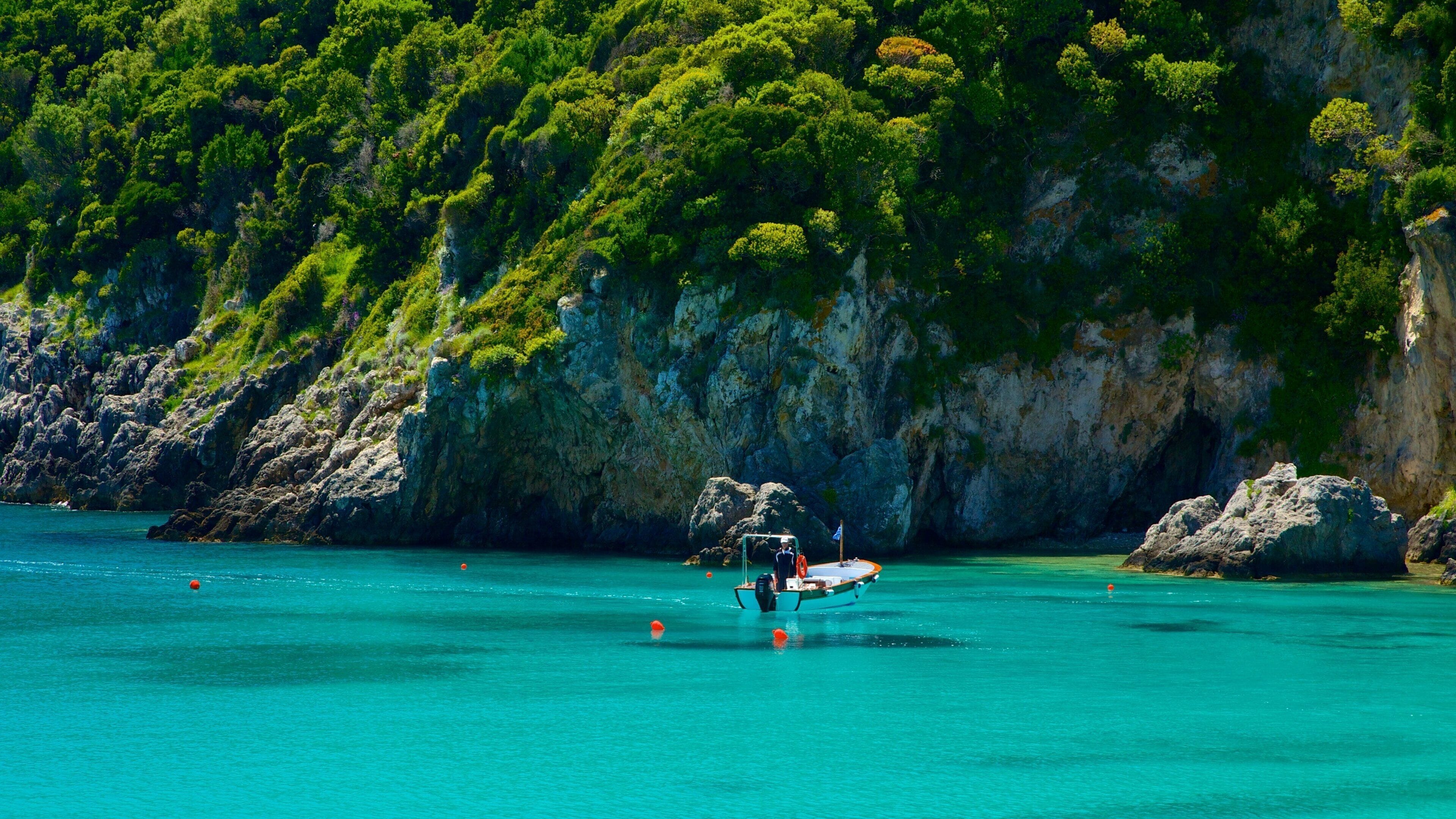 A boat anchored near a rocky coastline with lush green vegetation.