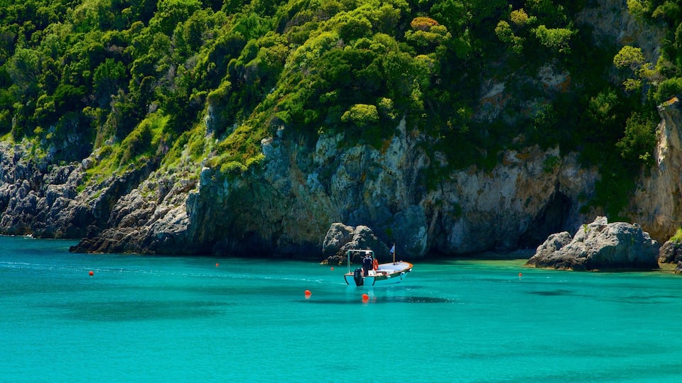 A boat anchored near a rocky coastline with lush green vegetation.