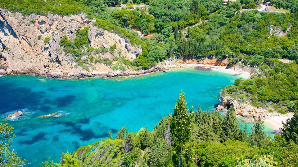 A coastal landscape with clear turquoise waters, rocky cliffs, and dense green vegetation.