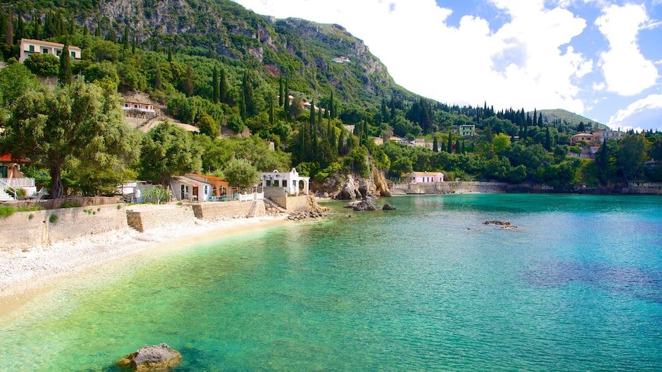 A coastal village with clear turquoise waters, terraced houses, and lush green hills.