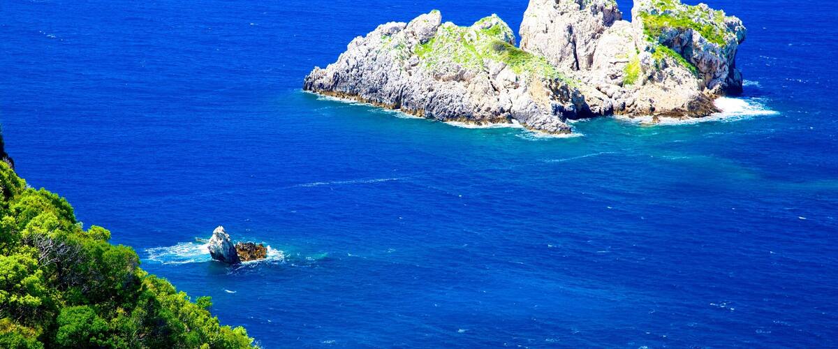 A rocky island surrounded by deep blue sea.