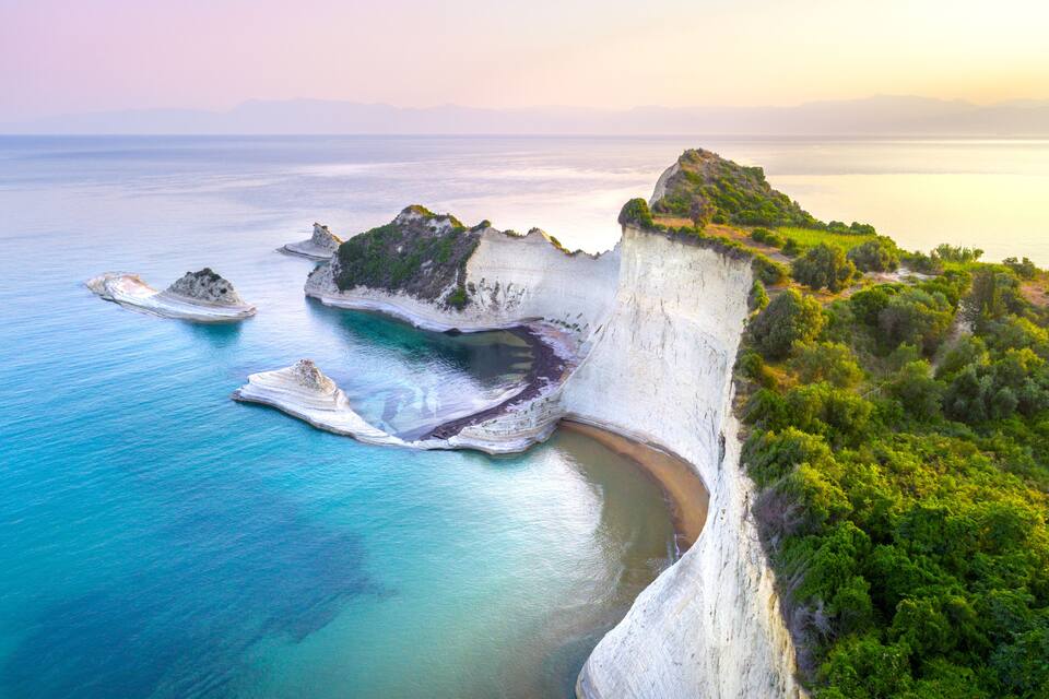 Un paysage côtier caractérisé par des falaises, des eaux d’un bleu limpide et une végétation luxuriante.