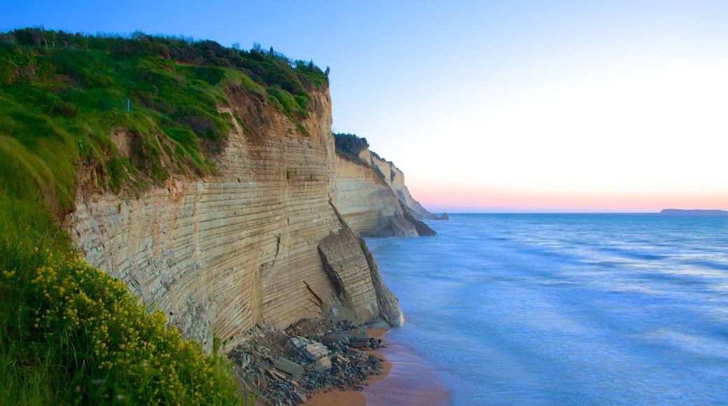 Sunset-strand toont een zonsondergang en rotsachtige kustlijn
