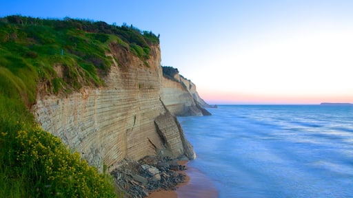 Sunset-stranden fasiliteter samt stenete kystlinje og solnedgang