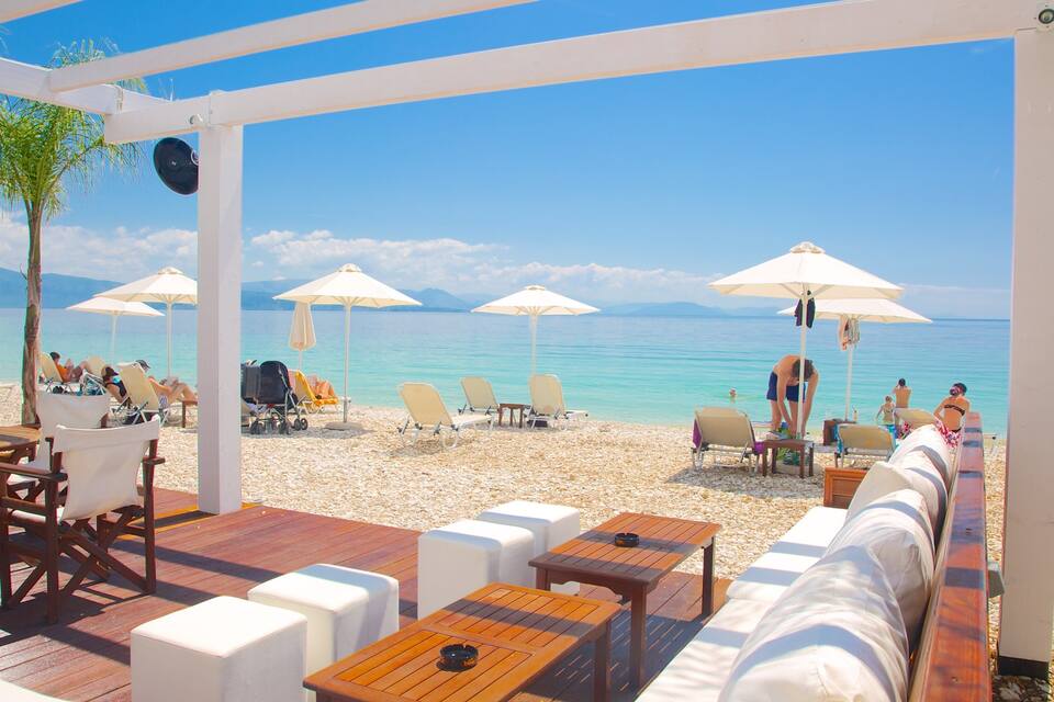 A beachside café with outdoor seating, umbrellas, and a view of the sea.