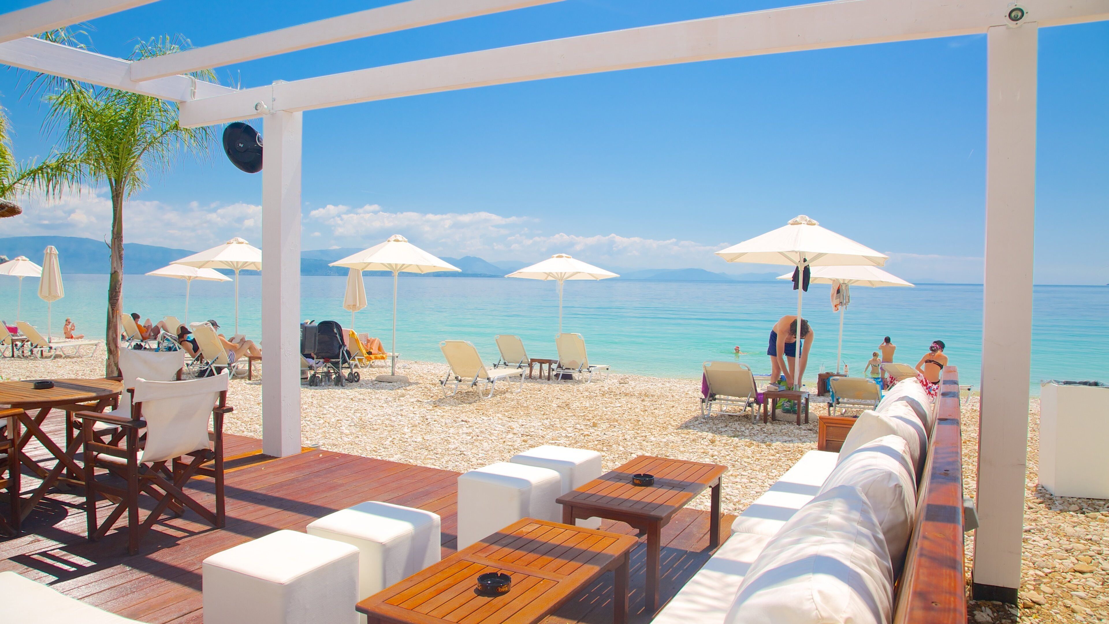A beachside café with outdoor seating, umbrellas, and a view of the sea.