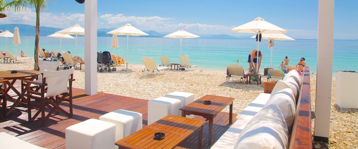 A beachside café with outdoor seating, umbrellas, and a view of the sea.