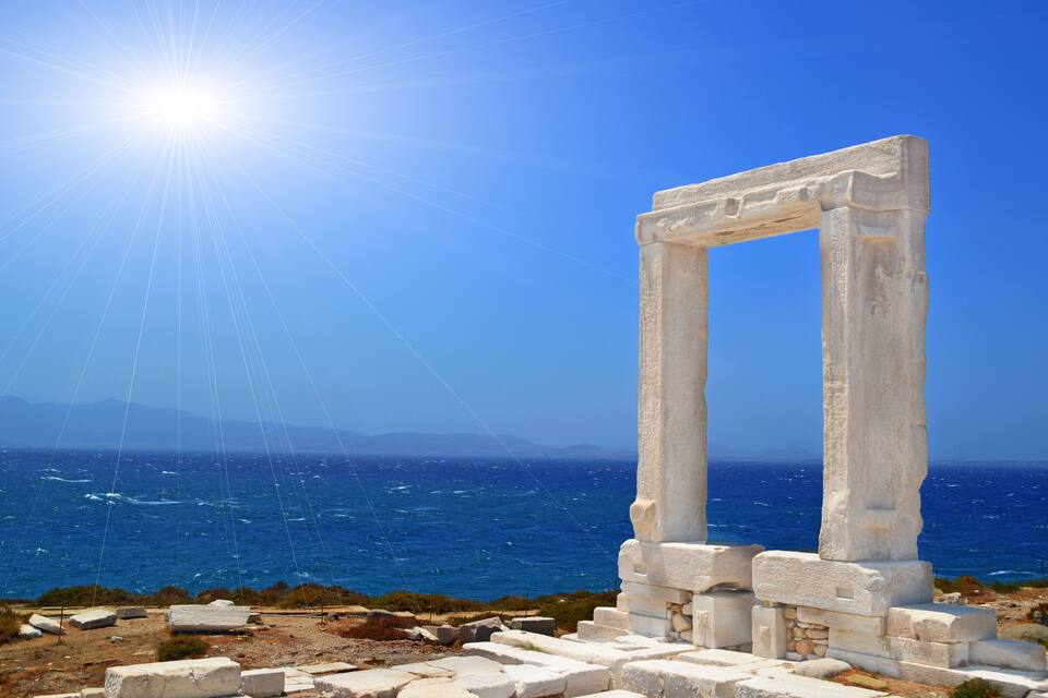 Ancient white stone ruins with a clear blue sky and the ocean in the background.
