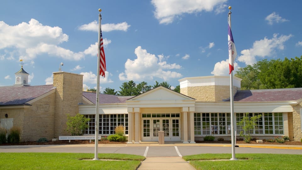 A library building with two flags, a clear sky, and trees in the background.