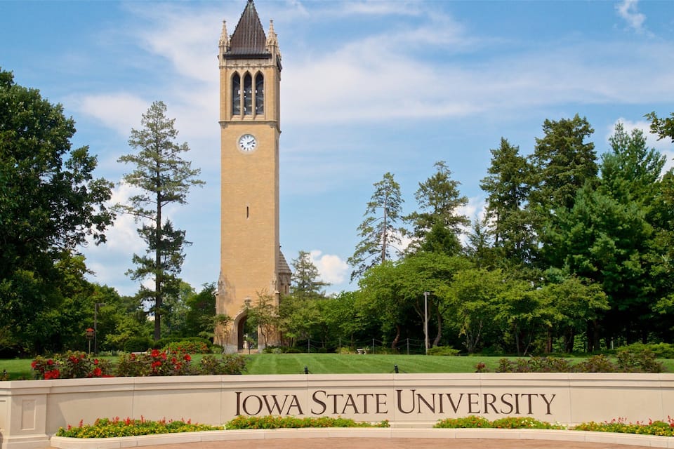 A clock tower at Iowa State University surrounded by lush greenery.