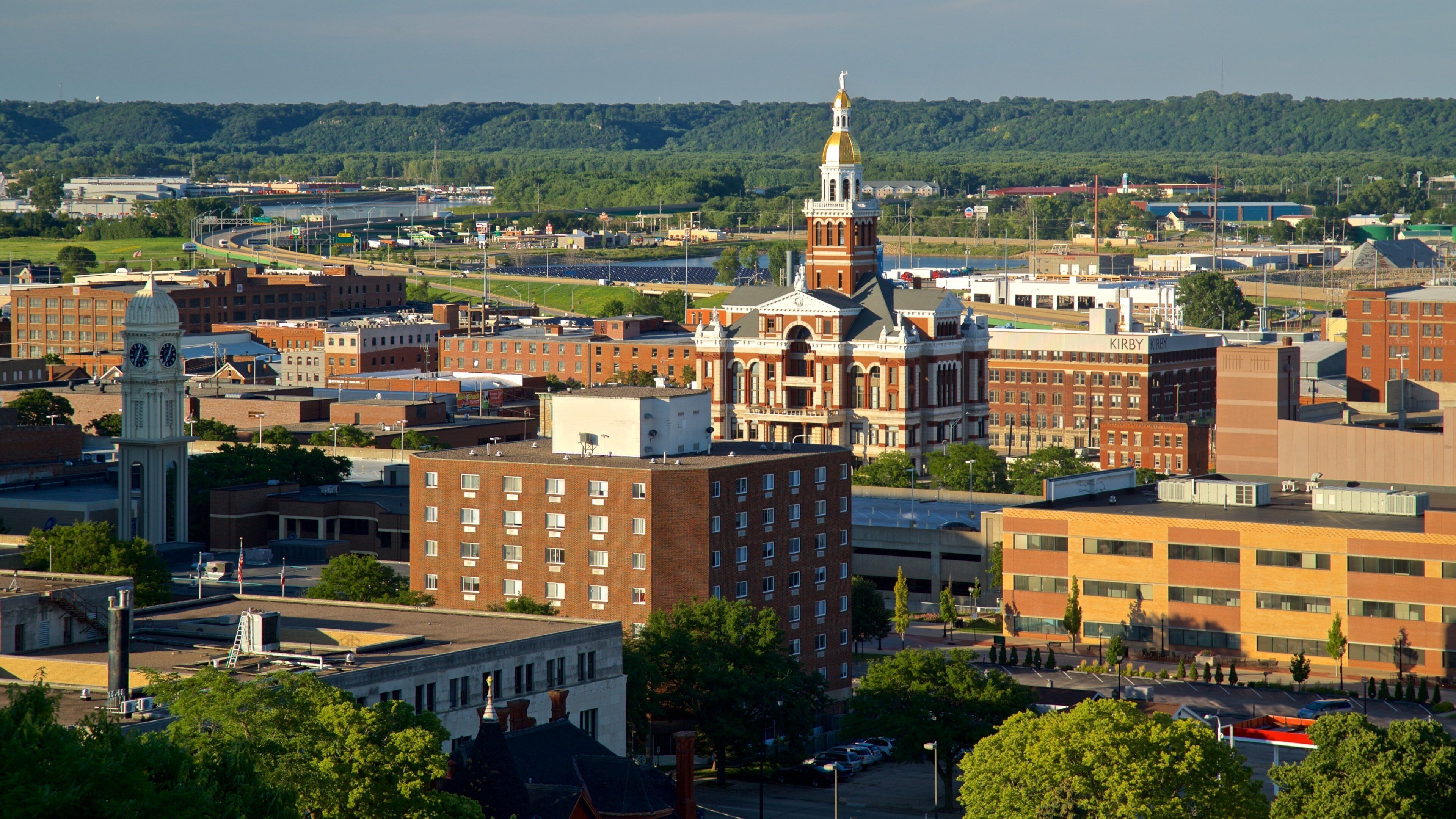 A cityscape with a prominent clock tower, a large red building with a dome, and a river in the background.