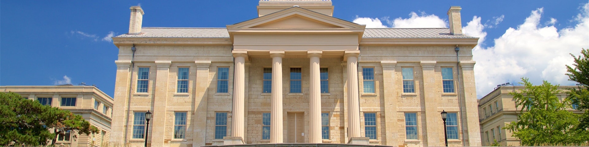 A large neoclassical building with a central dome, symmetrical windows, and a grand staircase leading to the entrance.