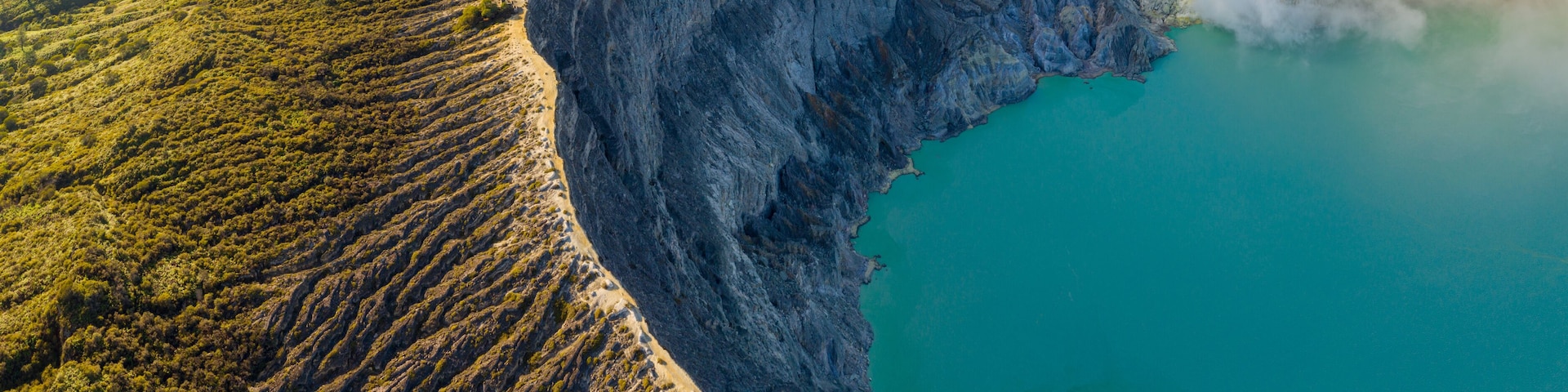 Un vaste lac de cratère, entouré d’un paysage accidenté et dominé par une montagne.