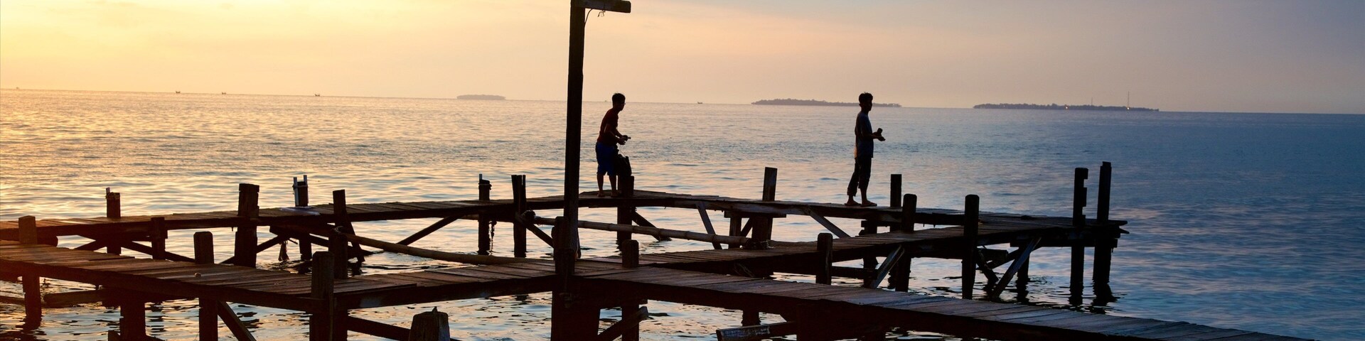 Un muelle de madera que se adentra en aguas tranquilas al atardecer.