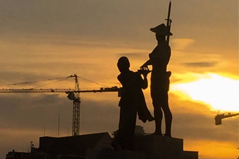 Silhuetter af en soldat og et barn mod en solnedgang.
