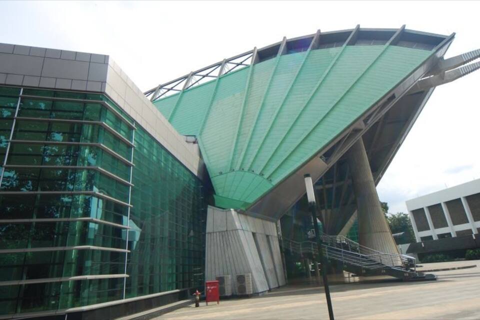 Um edifício moderno com telhado verde curvo e fachada de vidro.