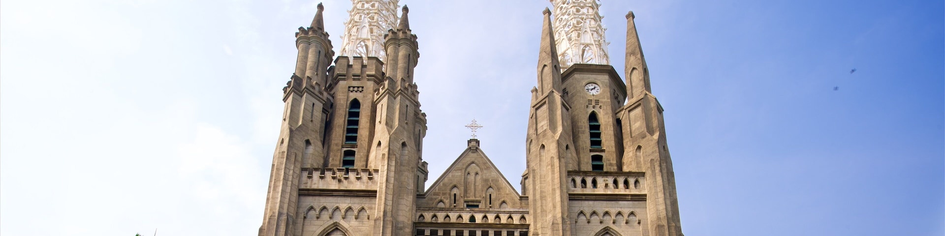 Uma catedral grande com duas torres altas e um vitral circular amplo.