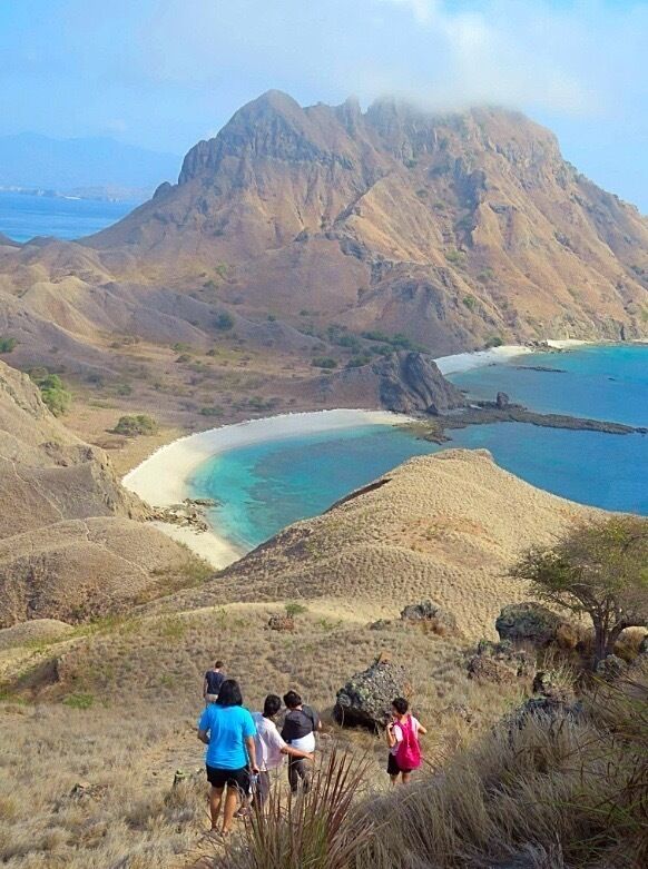 A mountainous landscape with a beach and clear blue waters.