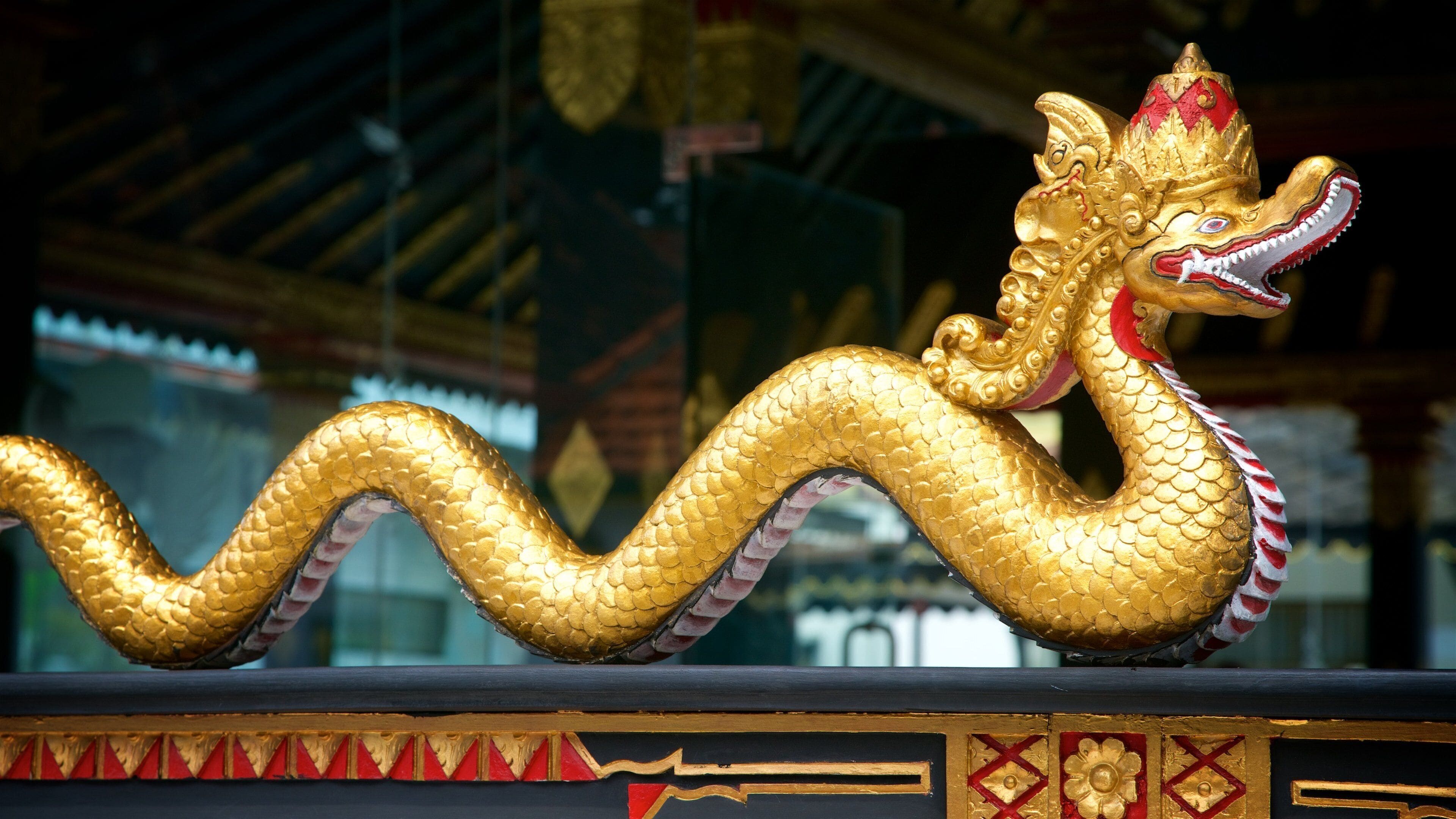 A golden dragon statue with intricate designs and a red and white patterned tail.