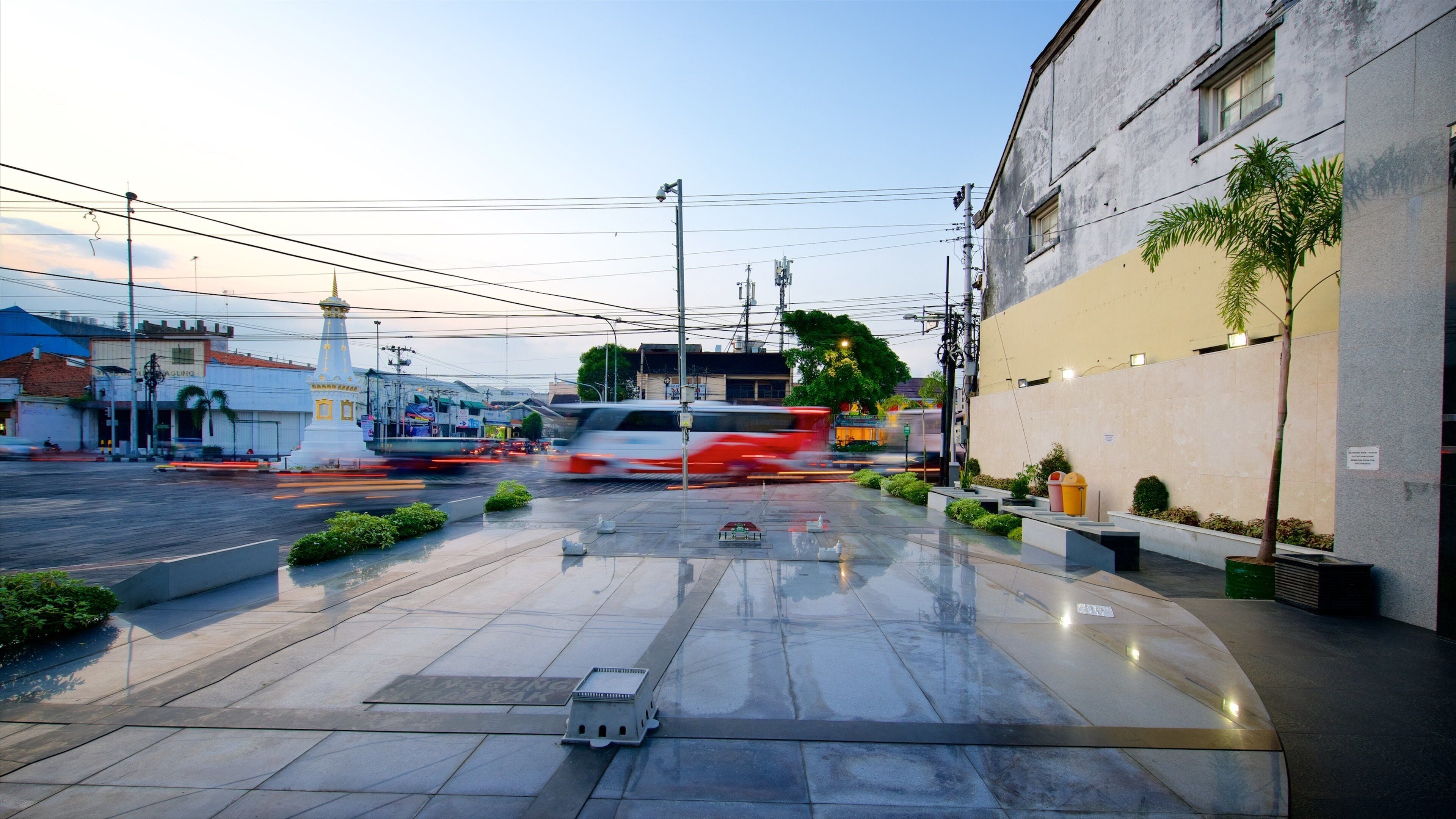A wet urban street with a white building, a red car, and a white van.