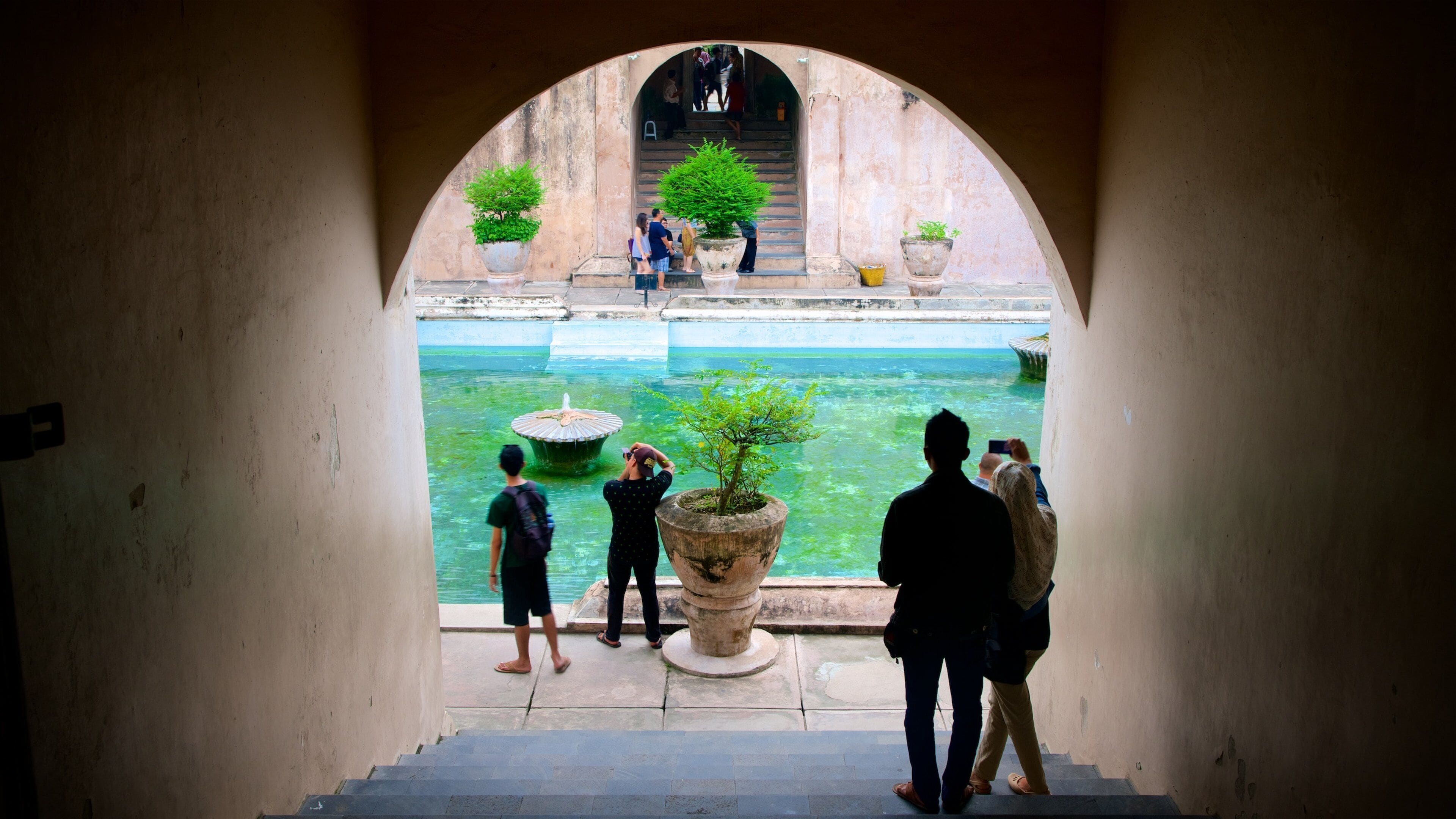 Water Castle showing a pool and heritage architecture as well as a small group of people