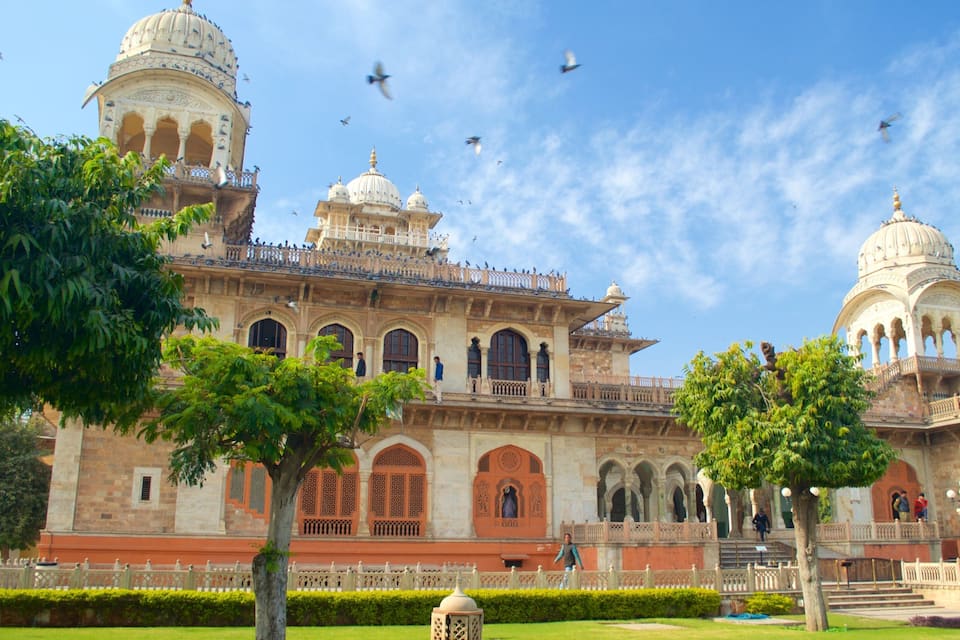 A historic building with domes and arches, surrounded by trees and a clear sky.