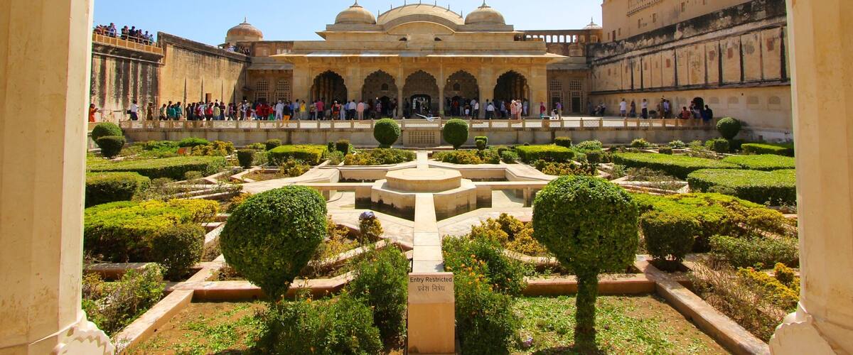 A historic building with arched gateways and a central water feature surrounded by manicured gardens.