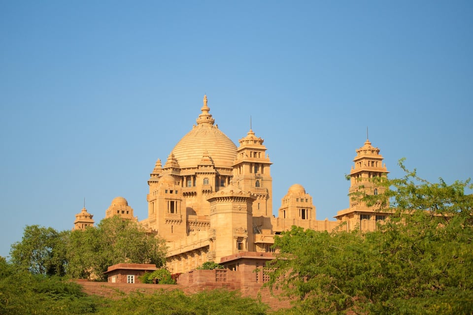 A large, ornate building with multiple domes and towers, surrounded by greenery.