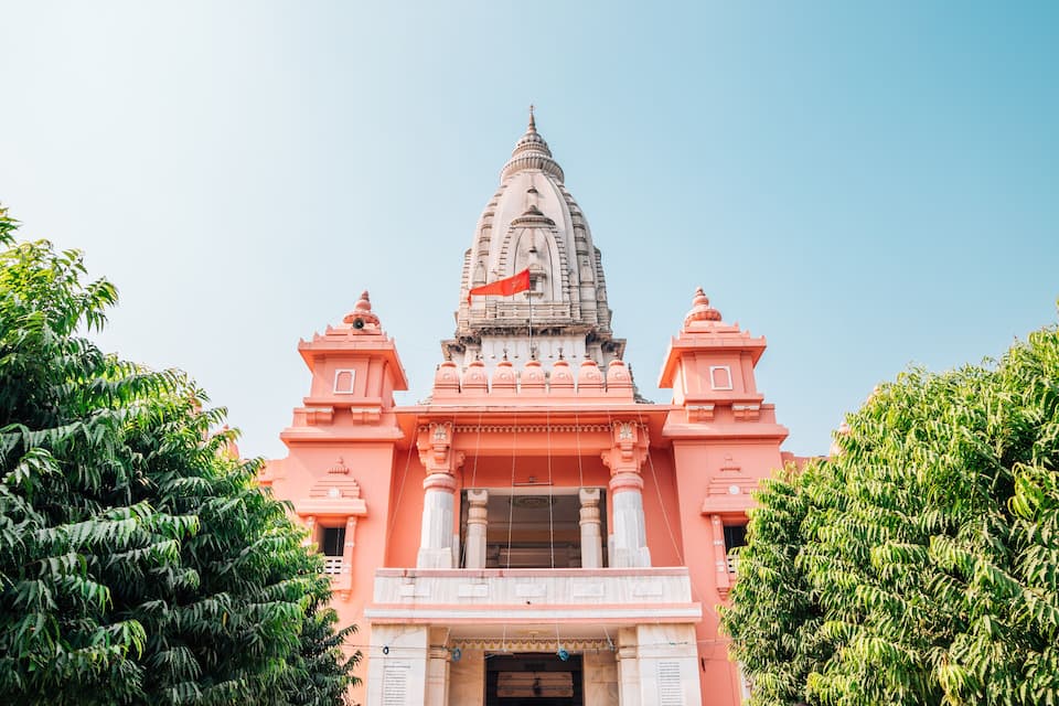 A pink temple with a pointed spire and a flag on top.