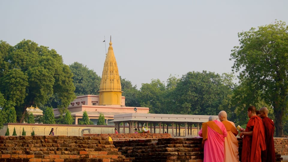 A temple with a tall spire, surrounded by trees and a brick wall.