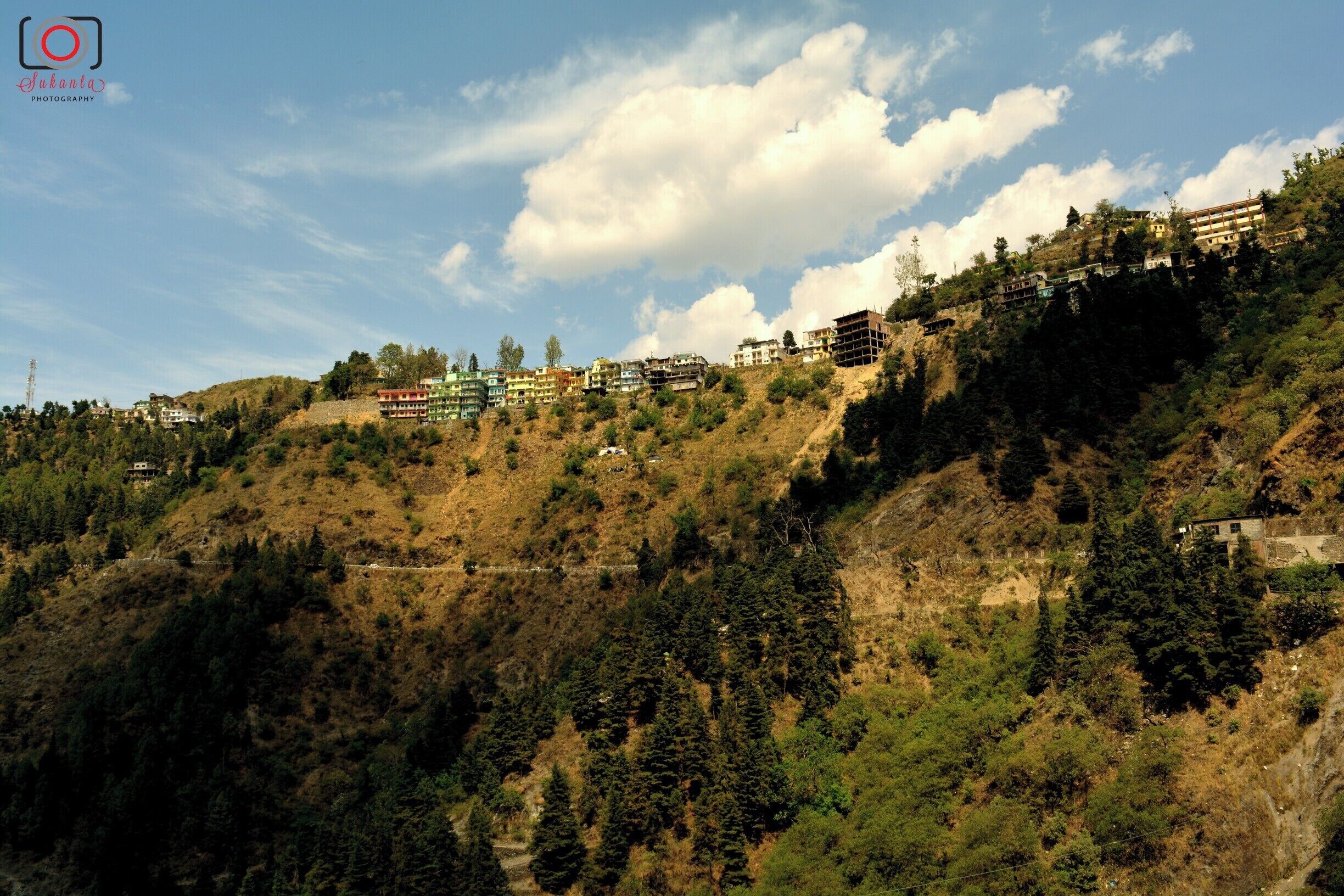 Kempty Falls is a magnificent waterfall and recreation area set in the lap of a green valley. It’s a favorite hangout of local residents, who come to cool off in waterholes, have fun with relaxed boating activities and enjoy scenic picnics. A British officer established Kempty Falls in the 1830s as a place for the British Raj to hold tea parties. The waterfall’s name is rumored to stem from the colloquial name of Camp Tea.
Follow the walkways and bridges that lead from the falls’ entrance to vantage points. Marvel as the milky-white water cascades down a cliff face before bouncing off rocks and into a manmade waterhole. Admire the verdant foliage that frames both sides of the waterfall. Listen to the invigorating sounds of the rushing water, which mingles with the excited cheering of visitors.
On a warm and sunny day you might want to take a refreshing dip in the inviting pool. Inflatable rings are available to rent and present the chance to float lazily on the shallow water. Stand directly beneath one of the branches of the falls to experience its full force. Around the pool, find restaurants serving traditional Indian snacks and a handful of shops selling curios.
A short walk past the main waterhole is a small water park, complete with a collection of terraced pools. Here you can enjoy safe swimming, ride waterslides and rent paddleboats.
Access to the falls is via a short cable-car ride that travels down a forest-covered mountainside. As you move deep into the valley, take time to check out the colorful Tibetan-style homes which sit precariously on the cliffs. An alternative way to get here is to walk down a series of hillside steps.
The waterfall is about a 30-minute drive from Mussoorie’s town center and easily accessible via auto-rickshaws and taxis. Combine your visit with a walk around nearby Happy Valley, a Tibetan community nestled amid a green forest. Visit a Buddhist temple and look inside to see artisan workshops.
Kempty Falls is open daily. There is a fee for the cable car and the attractions at the waterpark.