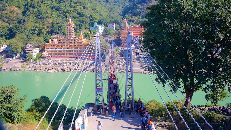 A suspension bridge over a river with a temple in the background.