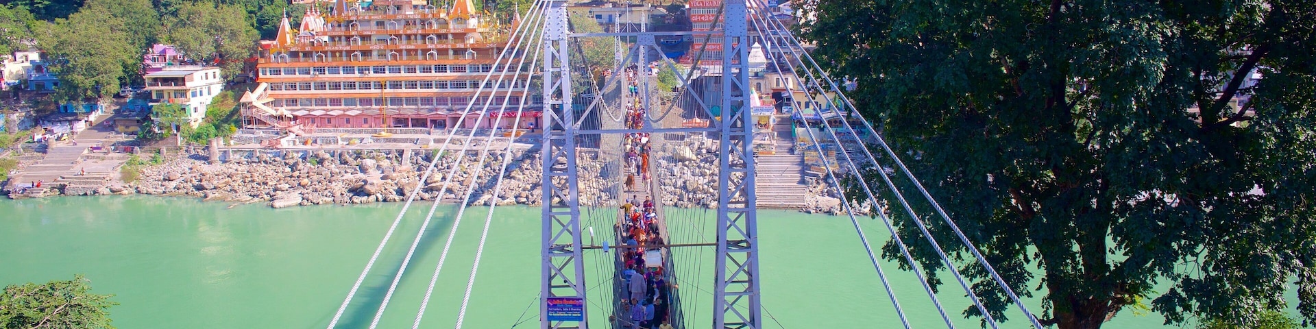 Lakshman Jhula which includes a river or creek, a suspension bridge or treetop walkway and a small town or village