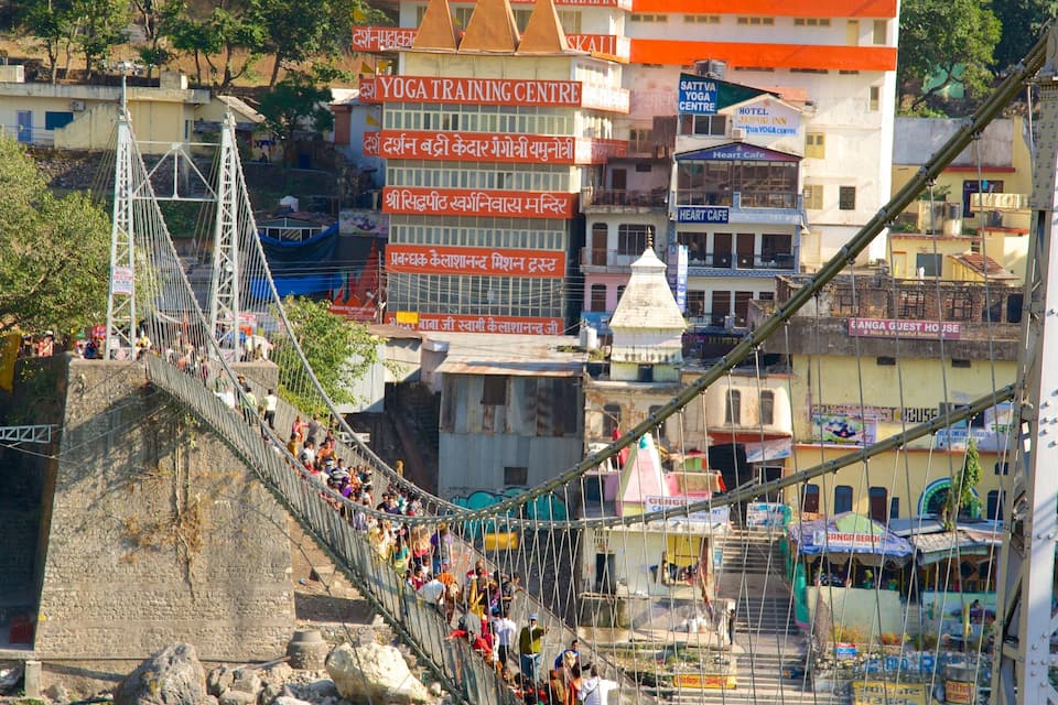 A suspension bridge with people crossing, surrounded by buildings with various signs in a local language.