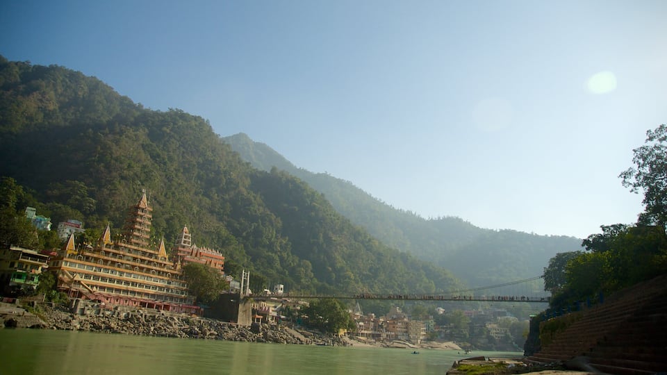 A river with a bridge, a temple, and mountains in the background.