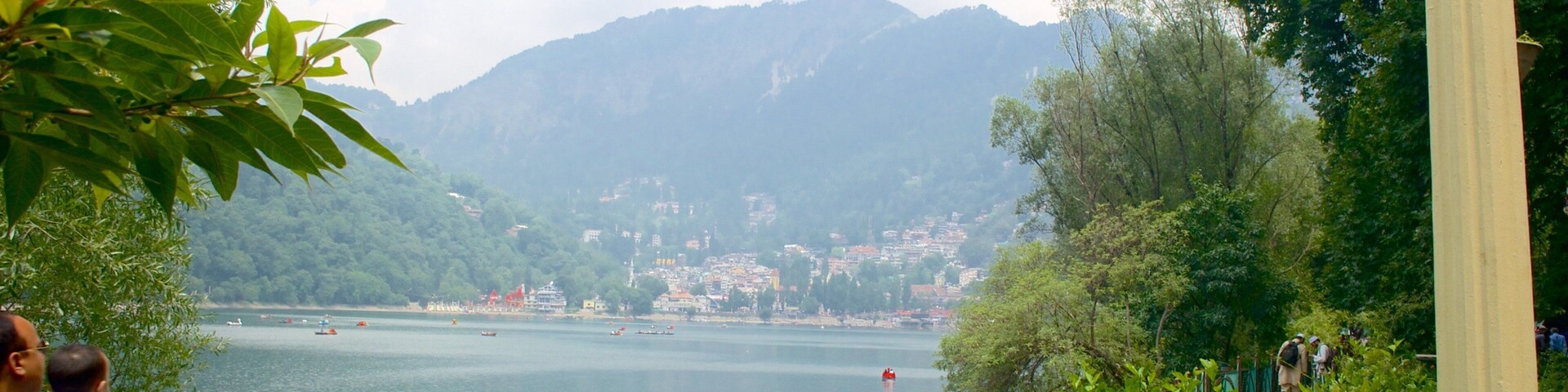 Un lago con barcos, una montaña al fondo y una cerca en primer plano.