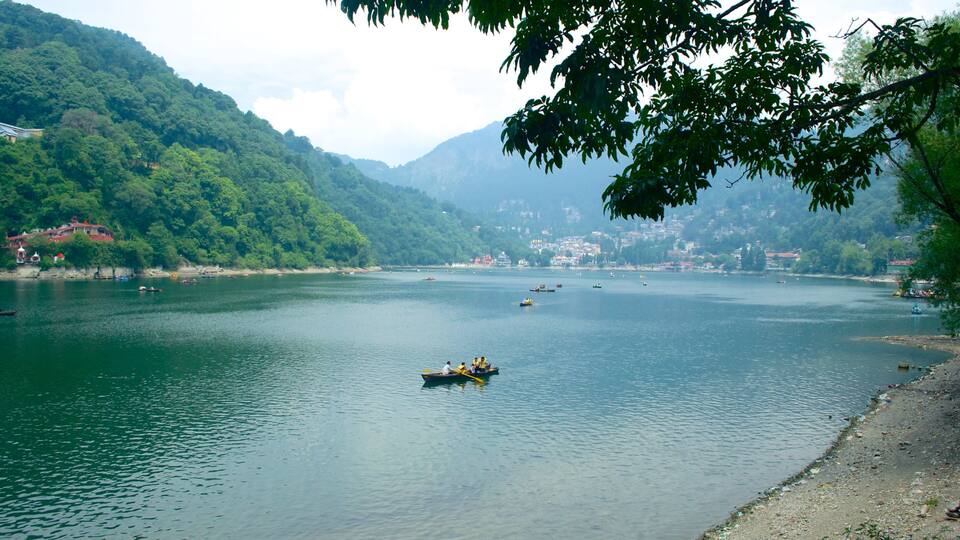 A calm river with boats, surrounded by lush green hills and a distant town.