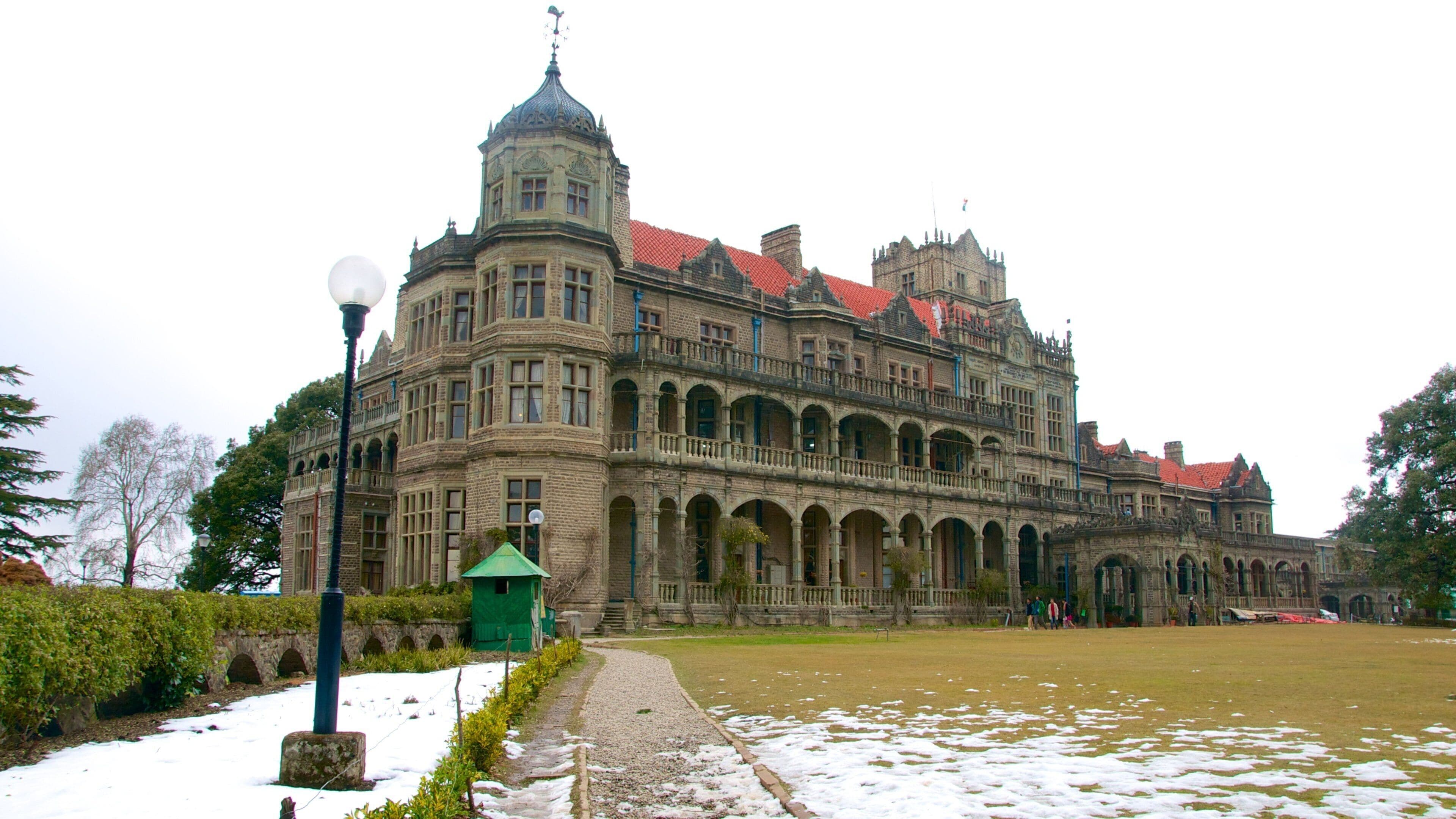 Um edifício grande e ornamentado, com telhado de telhas vermelhas e várias arcadas.