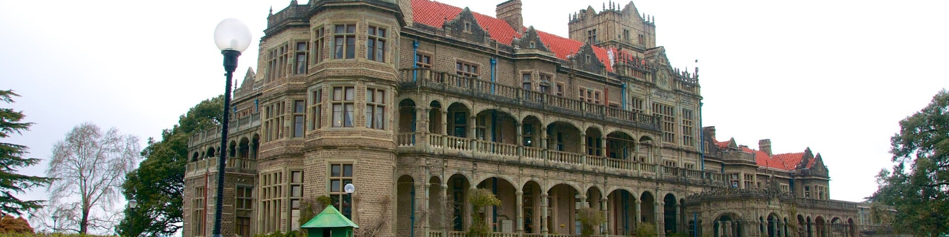 Um edifício grande e ornamentado, com telhado de telhas vermelhas e várias arcadas.