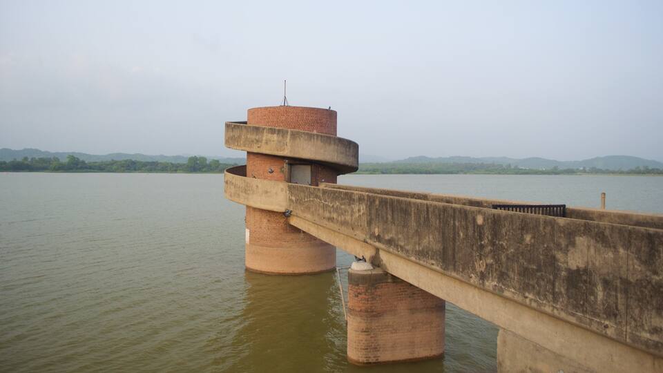 A bridge with a cylindrical tower and a concrete walkway over a river.