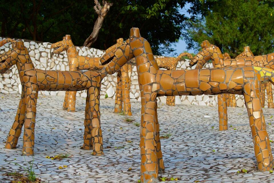 A mosaic sculpture of giraffes on a tiled ground.