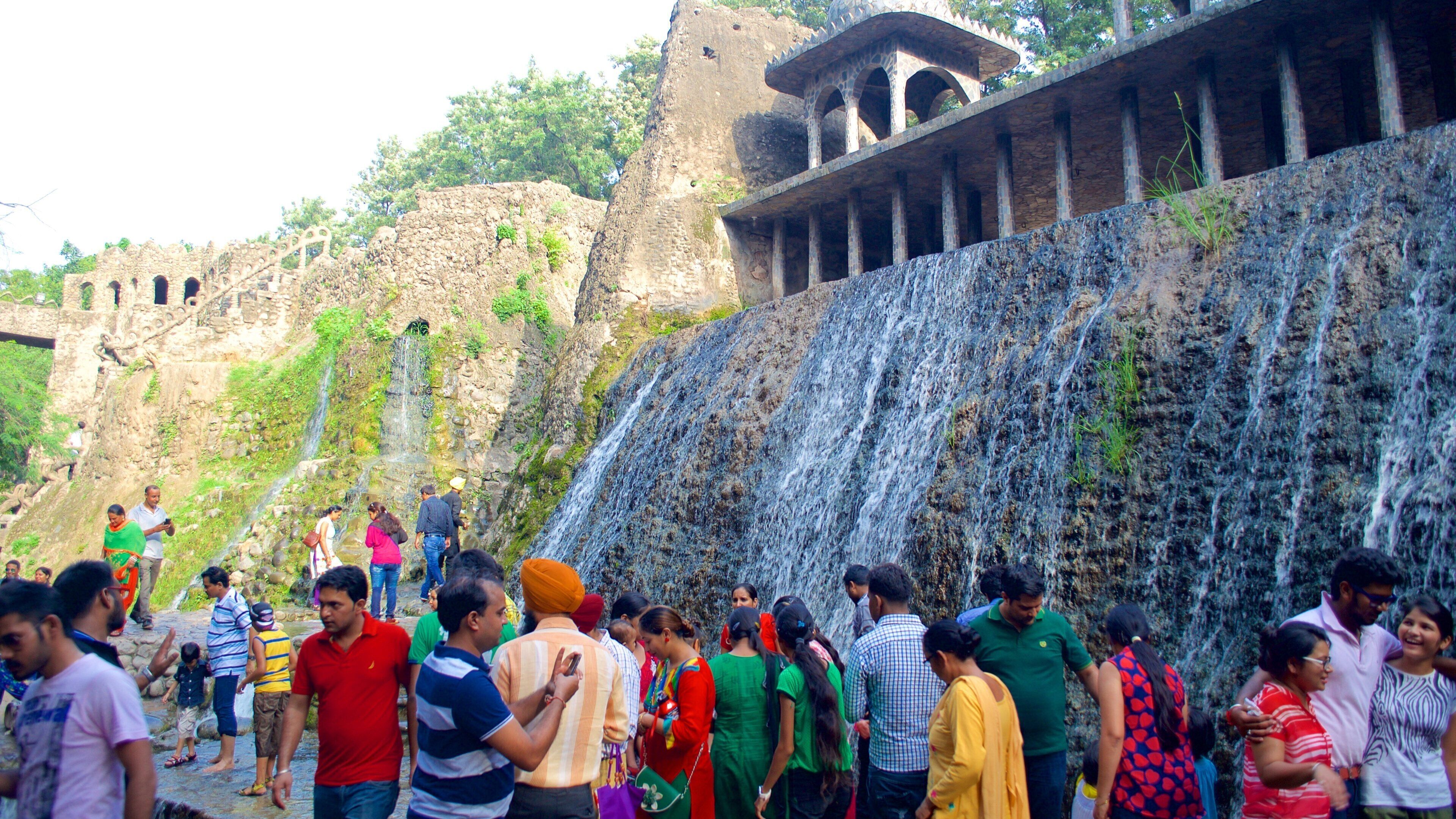 Jardín de Rocas mostrando un jardín y una cascada y también un grupo grande de personas