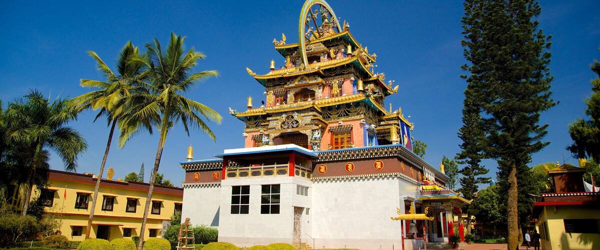 A traditional multi-tiered temple with ornate golden decorations, surrounded by palm trees and other greenery.