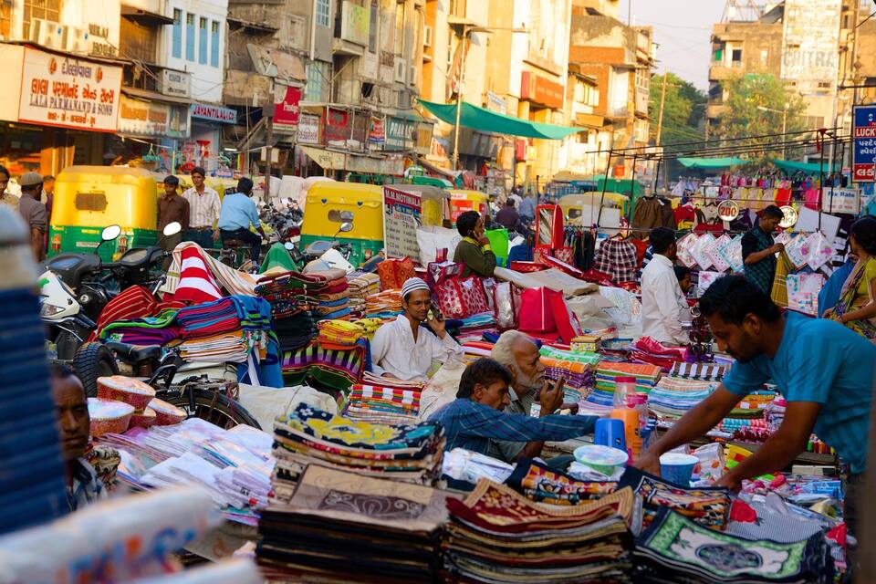 A bustling market with various stalls selling textiles and fabrics.