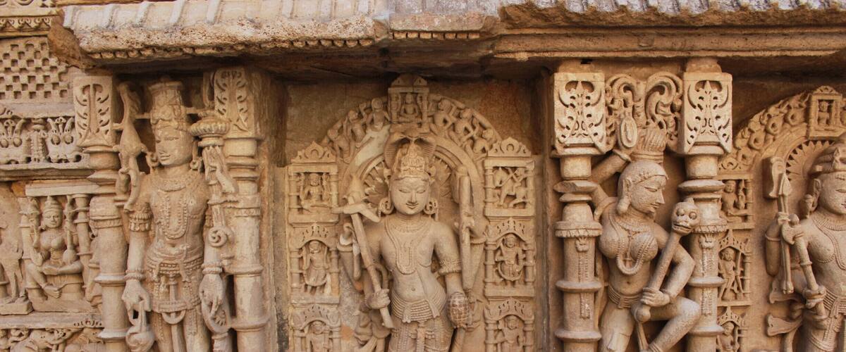 Detailed stone carvings of deities and mythological figures on a temple wall.