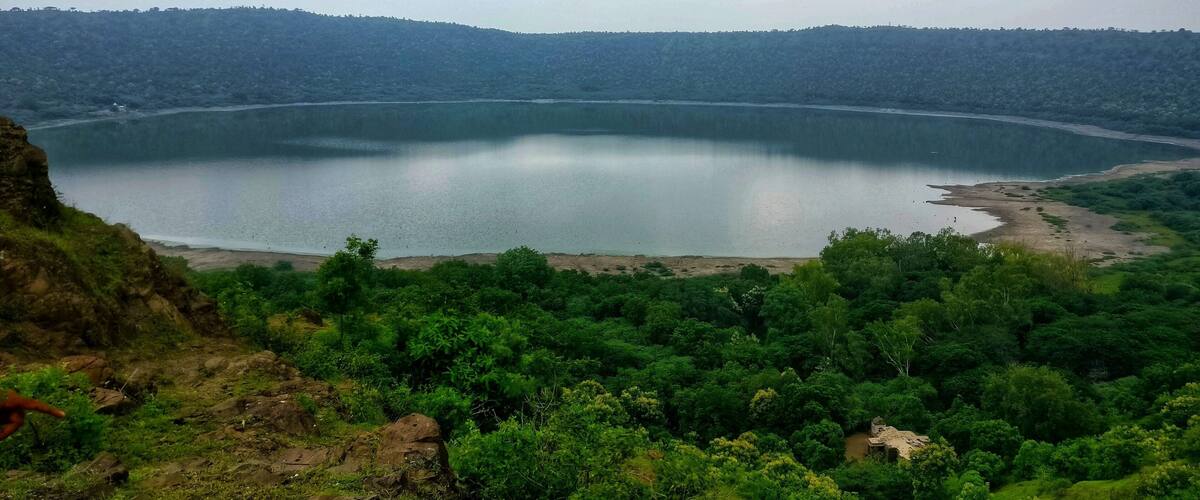 A large lake surrounded by dense green forest and hills.