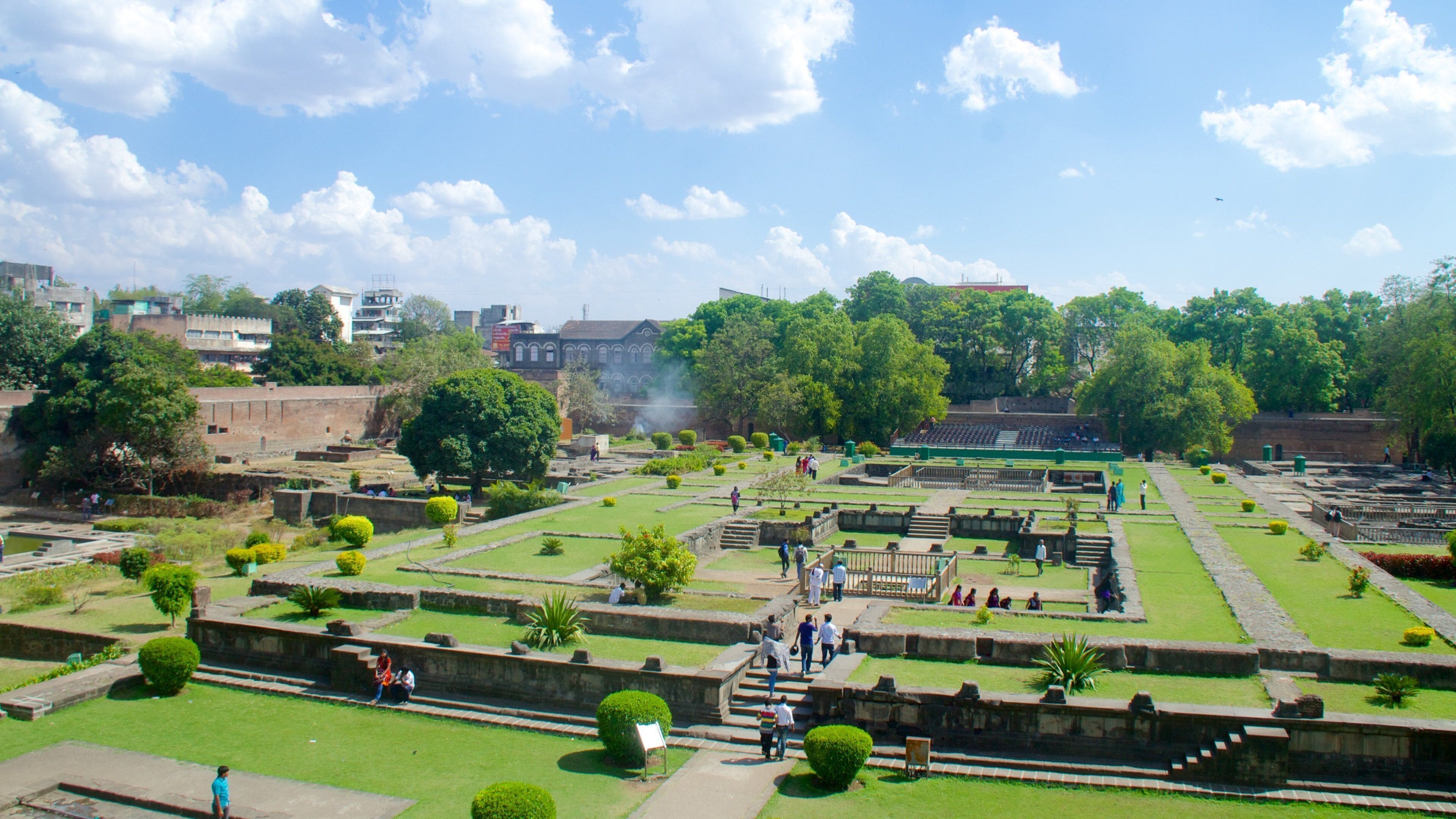 A historical site with ruins, green lawns, and trees.